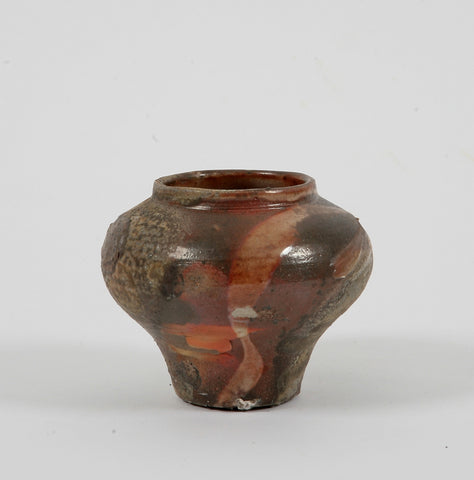 A small ceramic vessel with a narrow base and a rounded upper half with an open rim 