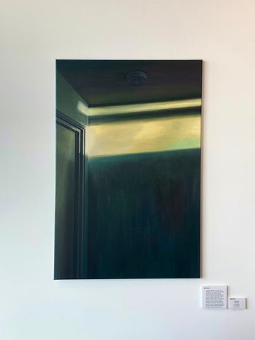 An oil painting of a sliver of yellow light illuminating a dark green corner of a room. On the ceiling is a smoke detector.