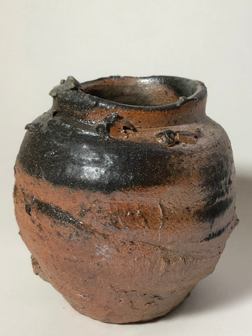A small ceramic vessel with a wide textured surface and an open rim 